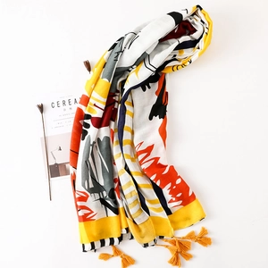 Détail d'une écharpe en coton et lin aux motifs abstraits colorés avec des glands jaunes