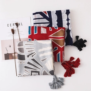 Détail de foulards en coton et lin à imprimé géométrique avec bordures à glands