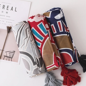 Détails de foulards en coton roulés avec imprimés géométriques et longues franges