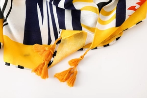 Détail d'une écharpe en coton avec imprimé géométrique et pompons jaunes faits main