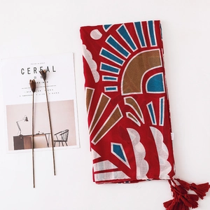 Détail d'une écharpe en coton et lin rouge avec motifs géométriques et pompons à franges