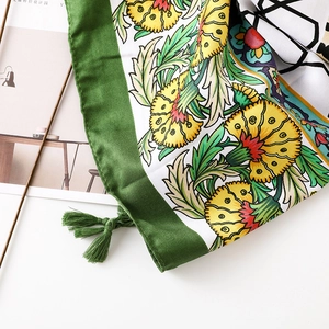Detail of cotton linen scarf with vibrant geometric patterns and green tassel accents