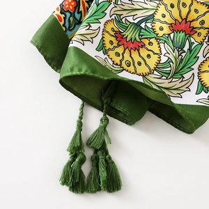 Detailed close-up of floral print cotton scarf with green woven tassels and fringes