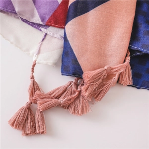 Detailed close-up of bohemian scarf with tassels and colorful geometric patterns