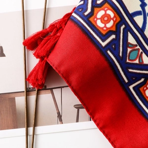 Macro detail of red ethnic scarf featuring bohemian patterns and dense fringe trim