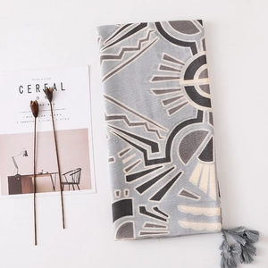 Détail d'une écharpe à imprimé géométrique avec franges à côté d'un magazine de mode