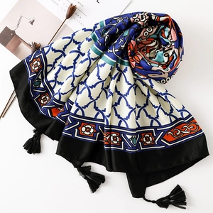 Macro view of Thai-style scarf with blue geometry, orange flowers and black tassels