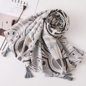 Détail d'une écharpe bohème à imprimé géométrique avec glands gris sur tissu en coton lin