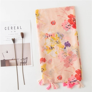 Floral print summer scarf in pink and orange tones with elegant tassels on white table