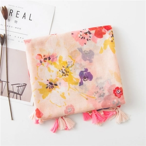 Detail of pink floral cotton scarf featuring colorful art blossoms and dual-color tassels