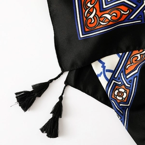 Close-up of ethnic geometric pattern and handmade black tassels on cotton linen shawl