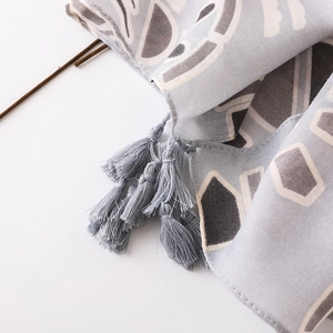 Détail de l'écharpe en coton et lin à motifs géométriques et pompons doux aux bords