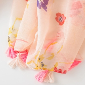 Detail of pink floral cotton scarf featuring colorful flower prints and fringe tassels