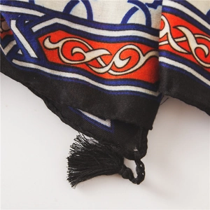 Macro detail of ethnic printed shawl featuring intricate patterns and black tassel edges