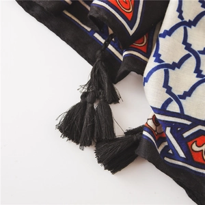 Detail of ethnic print scarf with black tassel fringe on lightweight fabric textile