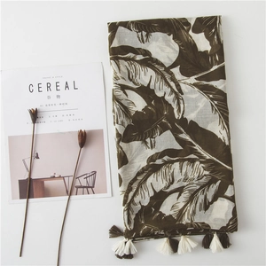 Long white scarf with tropical banana leaf print and tassels on minimalist background
