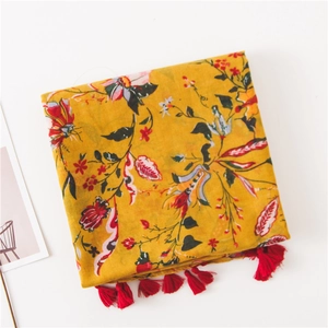Detail of floral ethnic scarf featuring yellow base print and red fringe tassels
