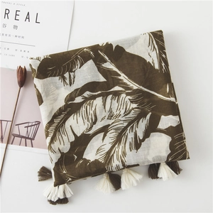 Detail of tropical banana leaf print scarf with tassels and breathable fabric texture