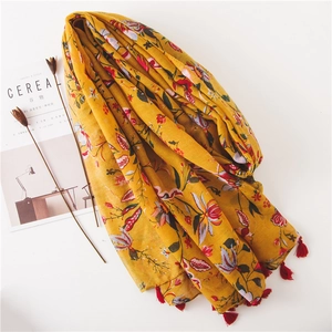 Ethnic yellow cotton linen scarf with floral print and red tassels on white background