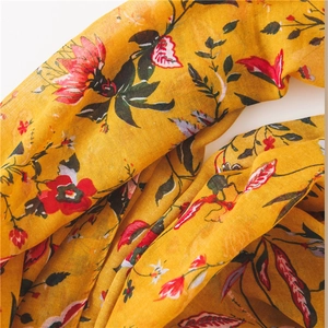 Detail shot of mustard yellow cotton linen scarf with red floral print and soft texture