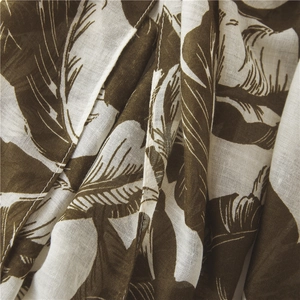 Close-up of cotton-linen scarf fabric with tropical green leaf print and hem stitching