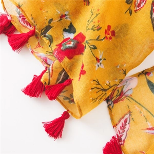 Close-up of floral print ginger scarf with handmade red tassels and fine edge stitching