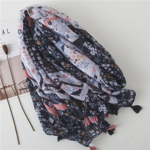 Navy blue floral scarf with geometric patterns and fringe tassels on a white surface