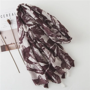 Long scarf with burgundy banana leaf print and tassel trim on white background