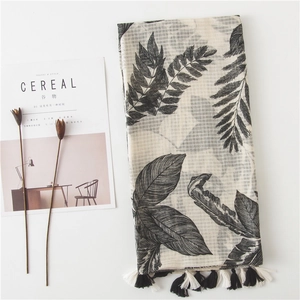 Linen cotton scarf with black tropical leaf prints and fringe trim for beach vacation