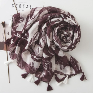 Long burgundy banana leaf print scarf with tassels on a minimalist white background