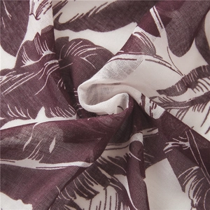 Detailed close-up of breathable white scarf fabric with red tropical leaf print texture