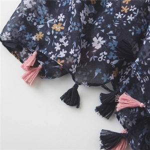 Detailed texture of navy floral fabric with soft blue and pink tassel fringe accents