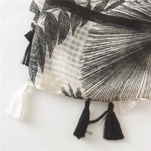Detail of leaf print scarf with black palm patterns and fringe trim edges