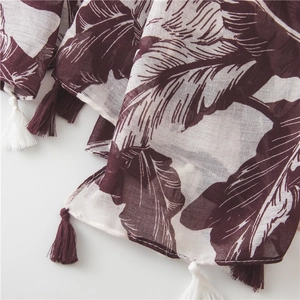 Detail of burgundy tropical leaf print shawl with breathable texture and fringe edge