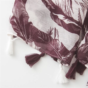 Detailed macro view of lightweight burgundy scarf with white banana leaf prints and fringe