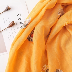 Detailed close-up of mustard yellow cotton linen scarf with floral embroidery patterns