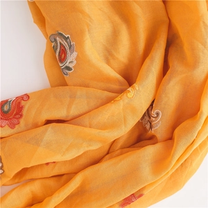 Close-up of ethnic style paisley floral embroidery on bright yellow linen cotton shawl
