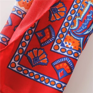 Nahaufnahme von Sonnenblumen-Strandtuch aus rotem Stoff mit blau-orangem Muster für den Urlaub