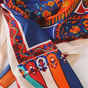 Detail of bohemian floral pattern on vibrant blue and orange silk feel scarf texture