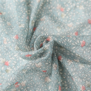 Macro shot of blue floral cotton scarf fabric with delicate leaf and pink flower patterns