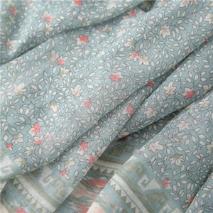 Close-up of floral cotton scarf showing grey-green fabric texture and ethnic pattern