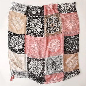 Détail de motifs mandala géométriques roses et pompons sur une écharpe en coton et lin