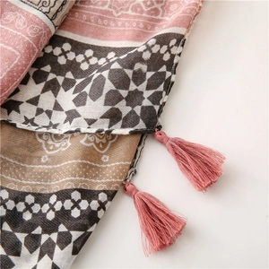 Détail d'une écharpe bohème en lin avec motifs géométriques et pompons roses élégants