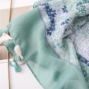 Close-up of mint green linen scarf with floral print and light blue tassel fringes