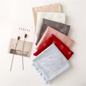 Detailed flat lay of cotton linen scarves featuring gold foil swallow and fringe edge