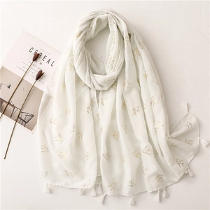 White linen scarf with golden swallow prints and tassels on a minimalist table setting
