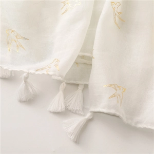 Macro detail of white linen scarf with gold swallow foil print and delicate fringe tassels