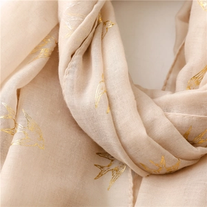 Detail of soft cream cotton linen scarf with elegant gold foil swallow bird patterns