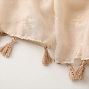 Detail of light beige cotton-linen scarf with golden swallow print and fringe trim