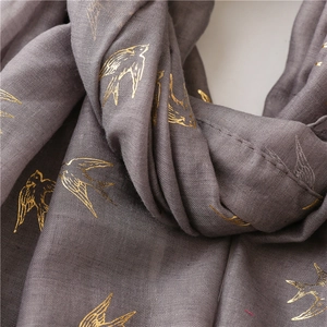 Detail of grey cotton linen scarf with elegant gold foil swallow pattern texture